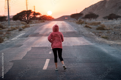 Girl running in sunset wearing pink hoody