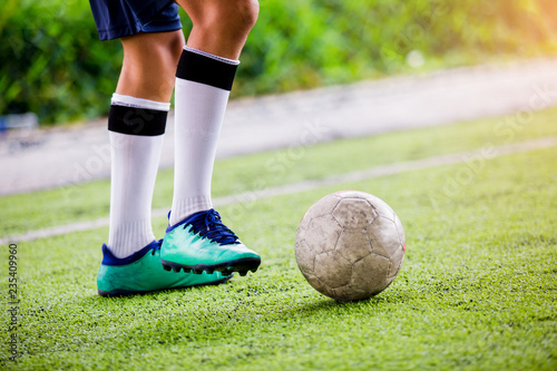 Soccer player speed run to shoot ball to goal on artificial turf.