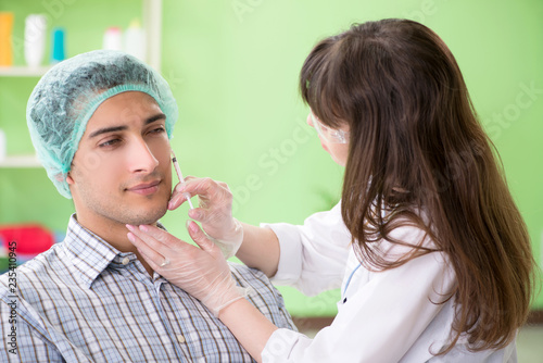 Plastic surgeon preparing for operation on man face