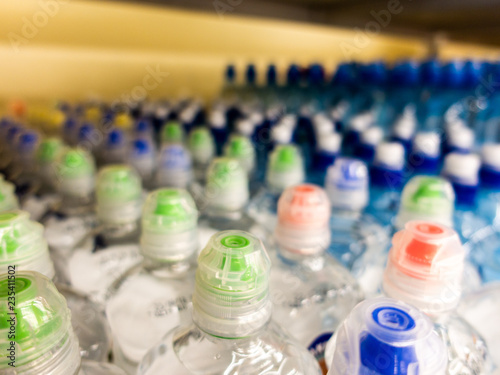 Plastic bottles with mineral water. Closeup on water bottles in raw and lines. Plastic bottles, colorful caps. Plastic bottles with water, lids. 