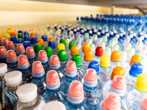 Plastic bottles with mineral water. Closeup on water bottles in raw and lines. Plastic bottles, colorful caps. Plastic bottles with water, lids. 