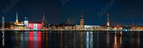 Night panoramic view across river to festive decorated Old Town in Riga, Capital of Latvia. Copy space in night sky