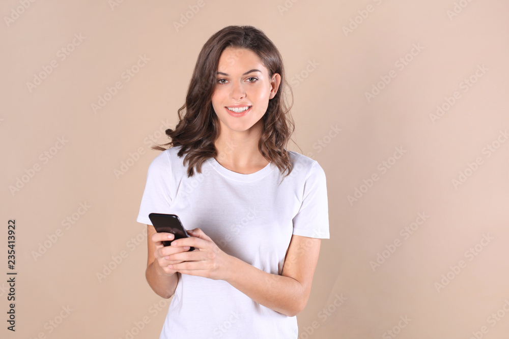 Young woman dressed in basic clothing isolated on beige background, using mobile phone. Young woman dressed in basic clothing isolated on beige background, using mobile phone.