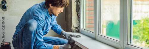 Man in a blue shirt does window installation BANNER, long format photo