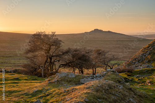 Stunning landscape sunset image over abandoned Foggintor Quarry in Dartmoor with raking soft sunlight over ruins and derelict buildings