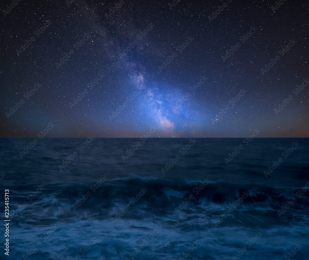 Vibrant Milky Way composite image over landscape of Waves breaking onto beach