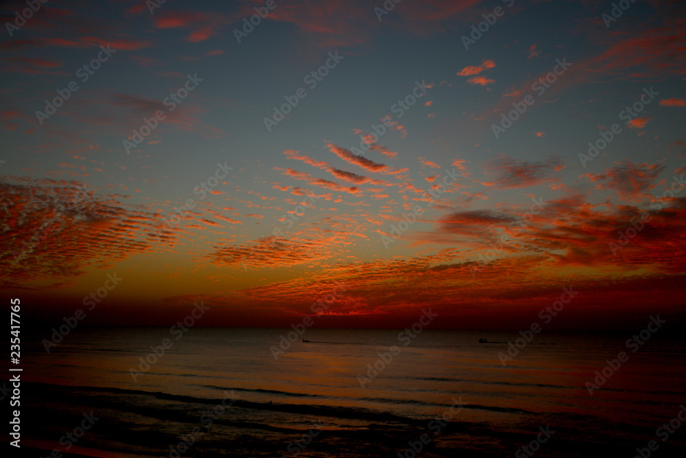 Fototapeta premium sunset at sea, red sun sits behind the horizon