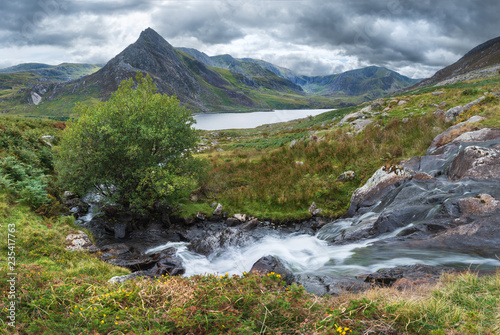 Stunning panorama landscape image of stream flowing over rocks near Llyn Ogwen in Snowdonia during eary Autumn with Tryfan in background