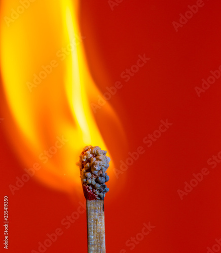 a burning match in front of red background photo