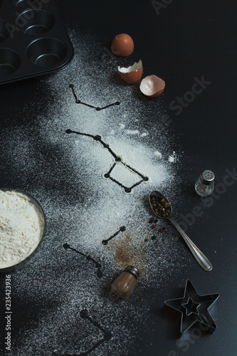 Constellations formed on a dark background with a twist of flour, cooking cupcakes and star cookies with black pepper