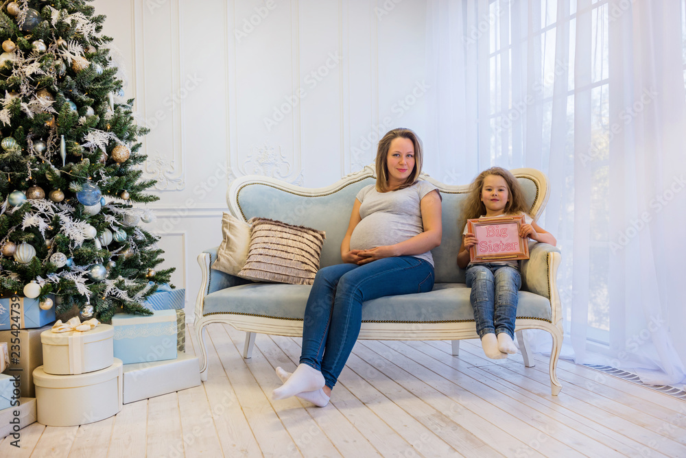 Beautiful pregnant woman sitting with doughter