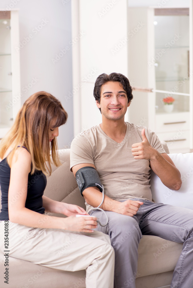 Wife checking husband's blood pressure Wife checking husband's blood pressure