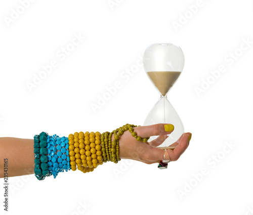 Female hand decorated with rings and braclets holding sand clock. Isolated on white backgroud. photo