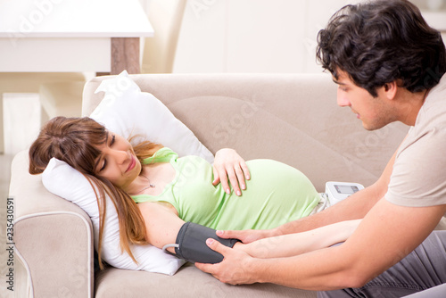 Husband checking pregnant wife's blood pressure