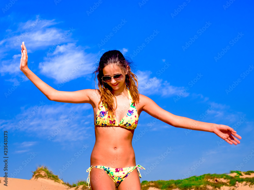 Beautiful young woman walking on the beach with a serene and happy face expression