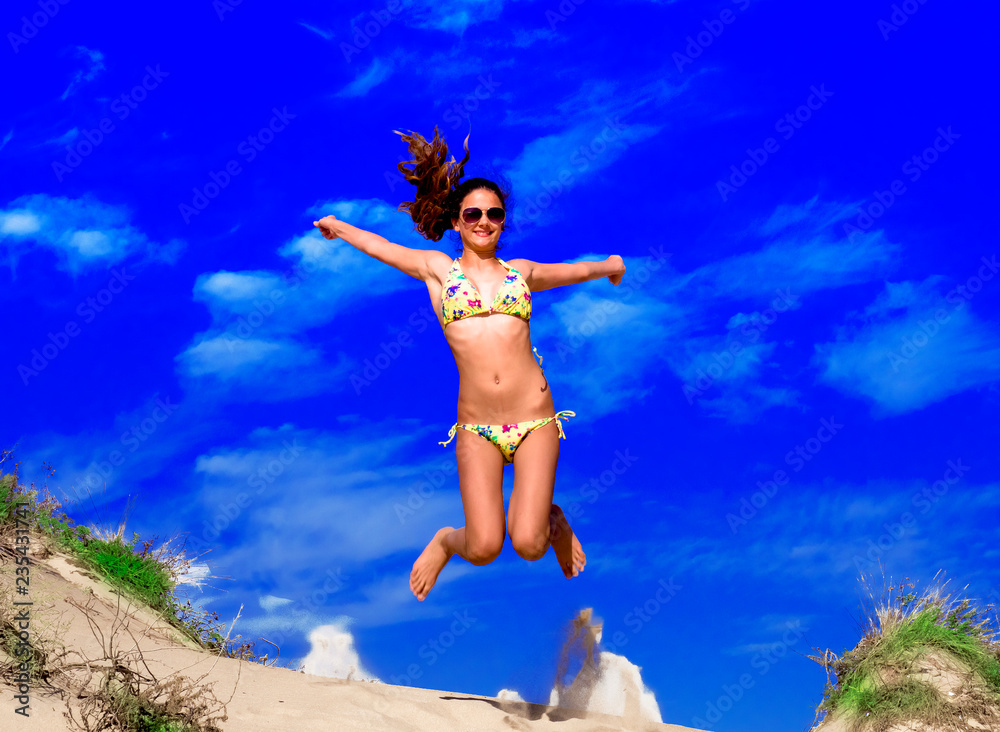 Attractive Girl in Bikini Jumping on the Beach Having Fun, Summer vacation holiday Lifestyle. Happy women jumping freedom on sand.