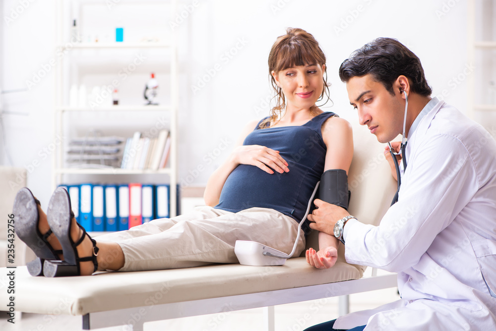 Young doctor checking pregnant woman's blood pressure Young doctor checking pregnant woman's blood pressure