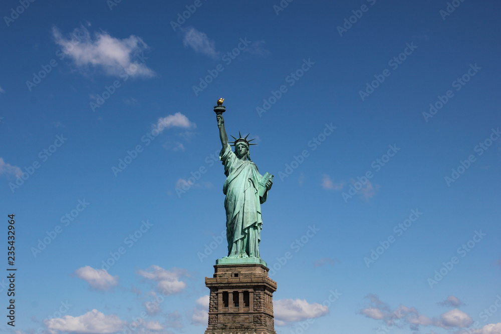 Fototapeta premium Statue of Liberty near New York city and Manhattan taken from a boat with a beautiful blue sky and some clouds in the background, United States