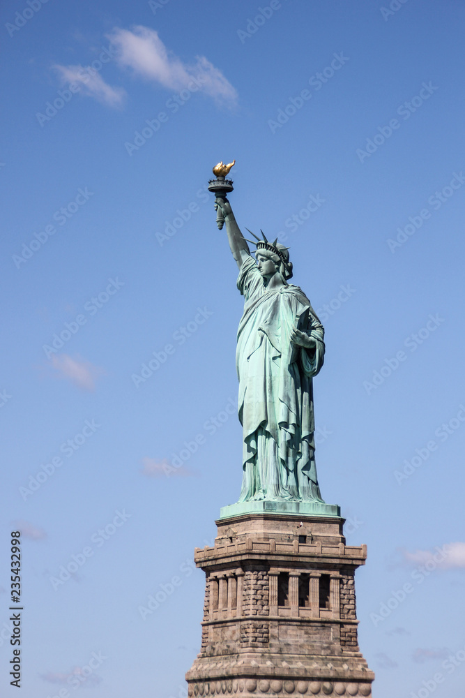 Fototapeta premium Statue of Liberty near New York city and Manhattan taken from a boat with a beautiful blue sky and some clouds in the background, United States