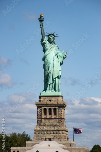Statue of Liberty near New York city and Manhattan taken from a boat with a beautiful blue sky and some clouds in the background, United States