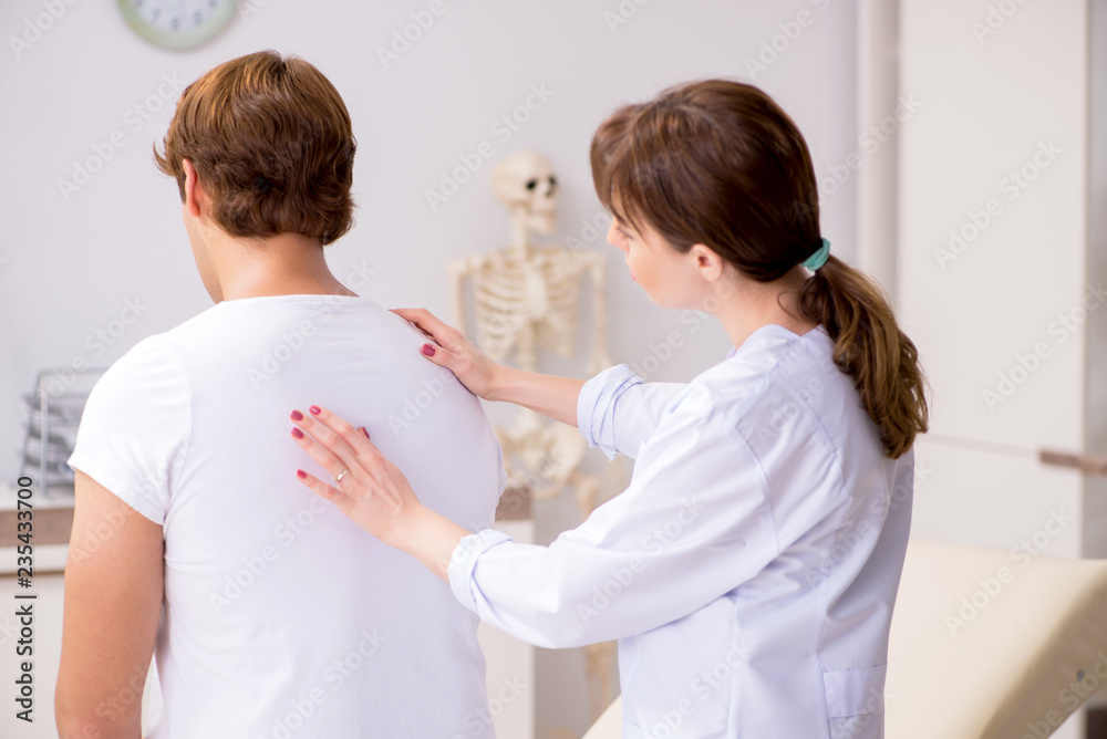 Obraz premium Male patient visiting young female doctor chiropractor 