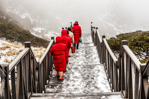 The staircase in the mountains and people in the red clothes climbing to the Cang Mountains (Cangshan) near Dali city, China. Foggy landscape. Travel Asia. photo