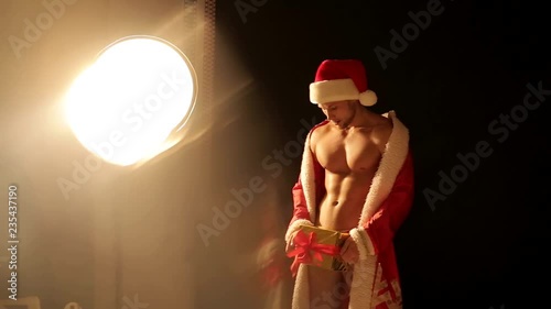 Christmas. Sexy Santa Claus. Young Muska dressed in Santa Claus hat and Santa Claus sack, white background in the studio photo