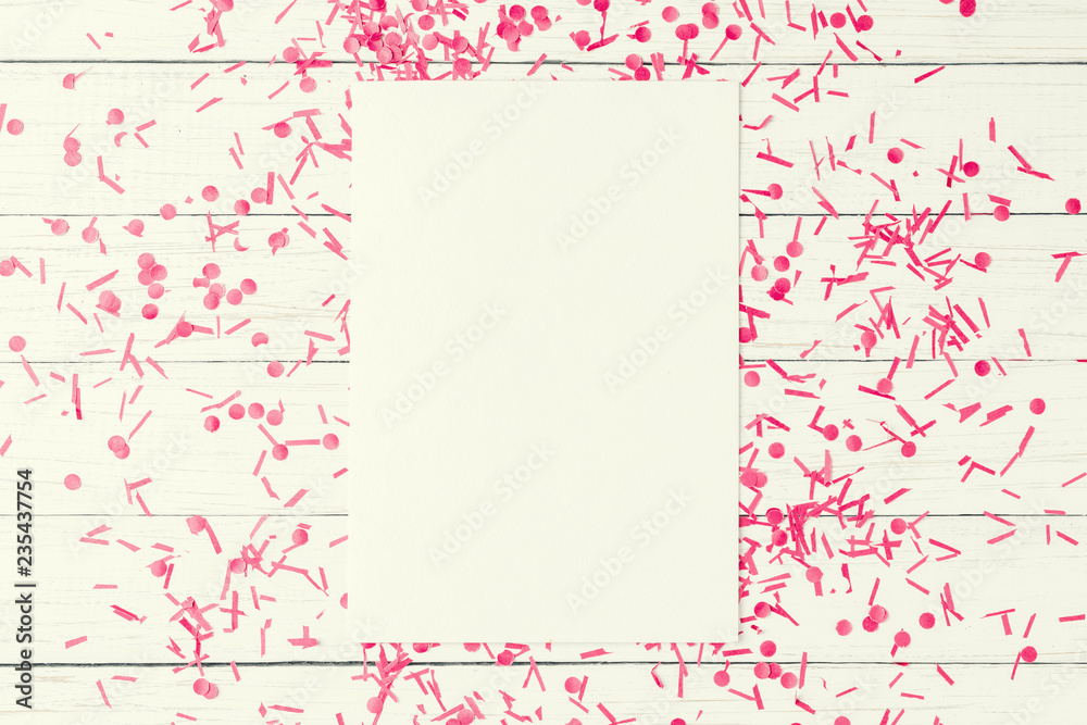 Empty white sheet with festive confetti on a white wooden background, top view