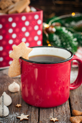 Red tea mug with cookies in Christmas decorations on a wooden table, selective focus