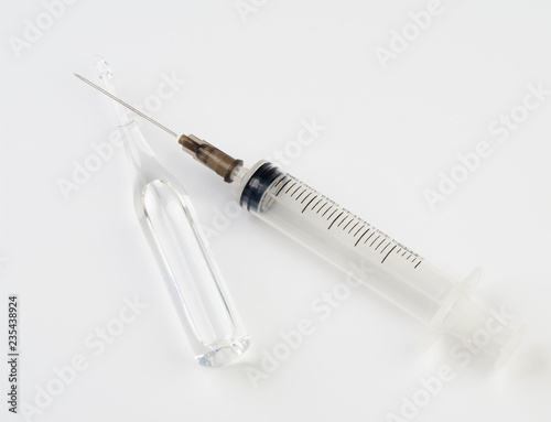 Medical syringe and glass ampoule with medicine on white background. photo