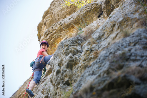 Photo of young sportswoman in protective helmet climbing on mountain
