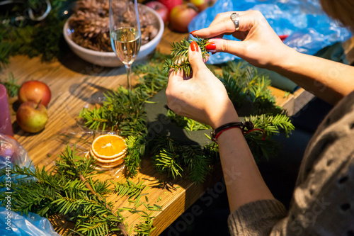 Women's hands above the table with accessories make a unique magic Christmas wreath by hand.