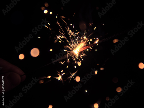 Hand holding a sparkler on black background