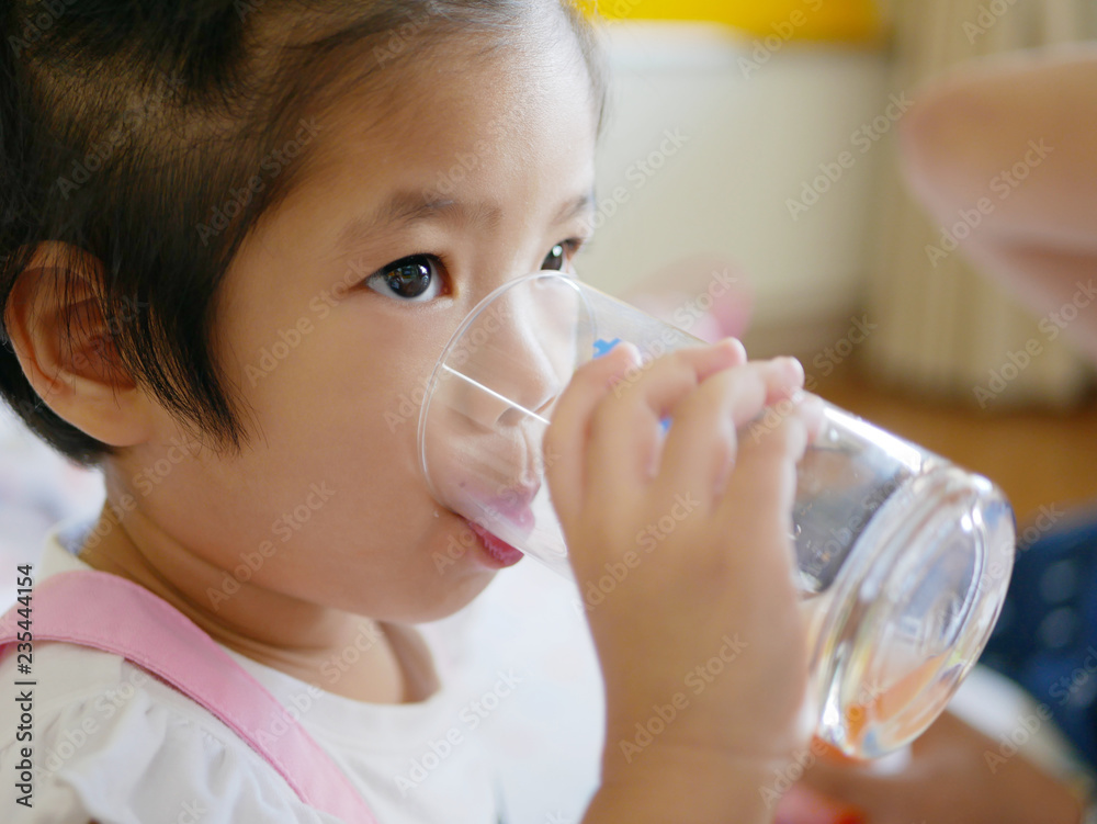 Little Asian baby girl, 34 months old, drinking water from a glass / cup by herself Little Asian baby girl, 34 months old, drinking water from a glass / cup by herself