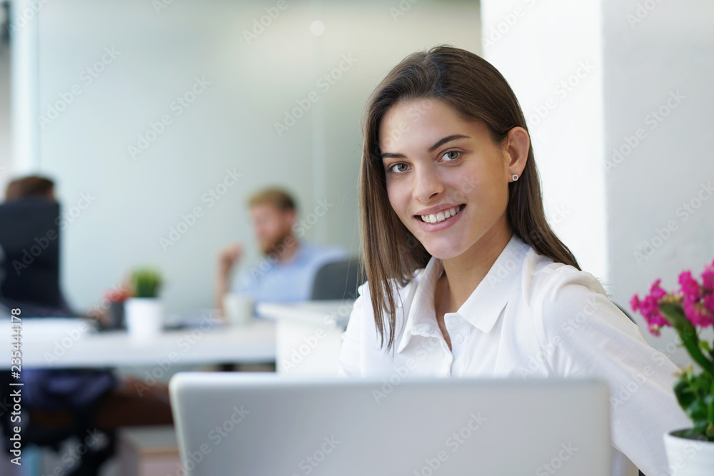 Beautiful business lady is looking at camera and smiling while working in office. Beautiful business lady is looking at camera and smiling while working in office.