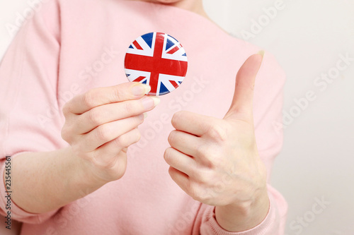 The flag of Great Britain, Union Jack printed on button badge, holding by woman