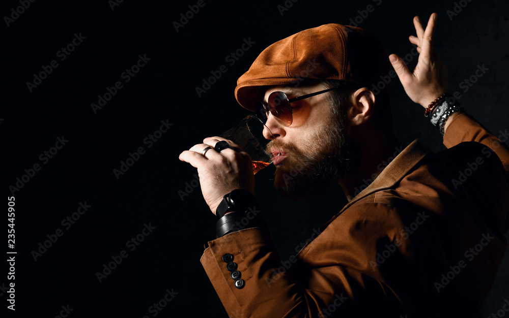 Brutal business man with beard and mustache in brown cap and jacket drink whiskey and dancing Brutal business man with beard and mustache in brown cap and jacket drink whiskey and dancing