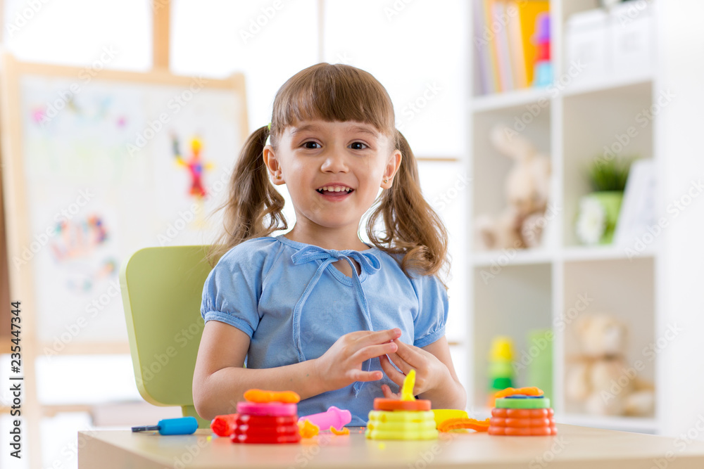 Children's creativity. Kid sculpts from clay. Adorable little girl moulds from plasticine on table in nursery Children's creativity. Kid sculpts from clay. Adorable little girl moulds from plasticine on table in nursery