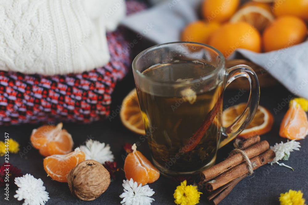 Tangerines, flowers, citrus in sraw basket, warm sweater, cup of tea and orange slices. Christmas winter background, wallpaper or greeting card. Top view, flat lay, background, copy spaces. 