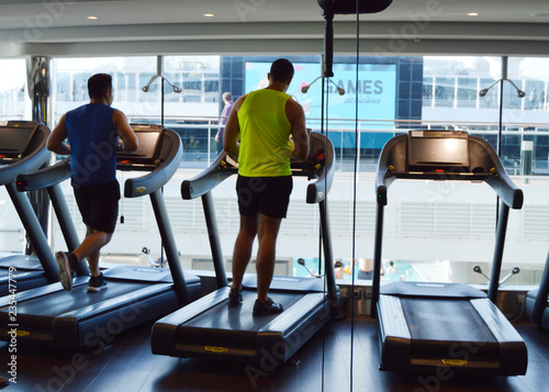 Fototapeta Naklejka Na Ścianę i Meble -  Modern gym with treadmills, people do sports on a cruise ship, the view from the back. MSC Meraviglia, 8 October 2018