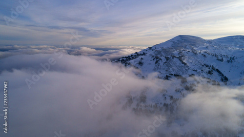 helicopter view of the peak of the mountain shrouded in fog at dawn © Wlad Go