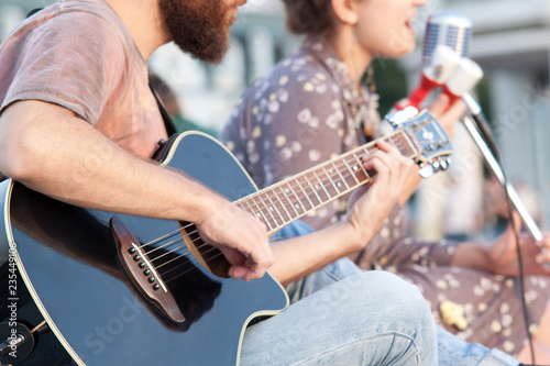 boy and girl sing a song on the street, girl sings, boy plays guitar