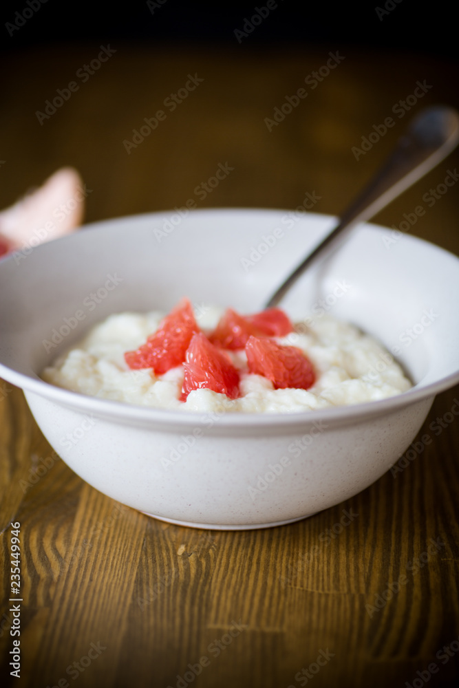 sweet boiled semolina porridge in a plate with slices of red grapefruit