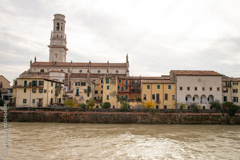 Group of old houses along the Adige river in Verona, Italy. In the picture we can recognize: the bell tower of the cathedral, the archbishop's palace, the stone bridge, the river.