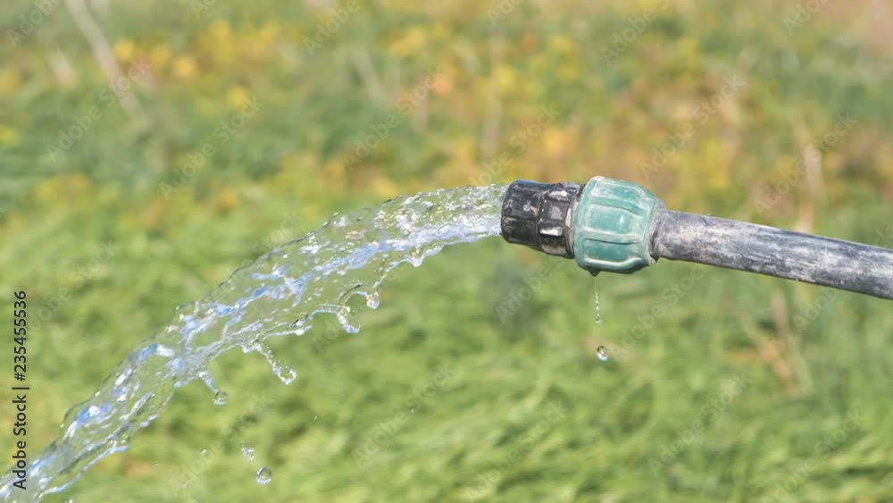 Clean water pours from the hose well outside on the grass background. Clean water pours from the hose well outside on the grass background.