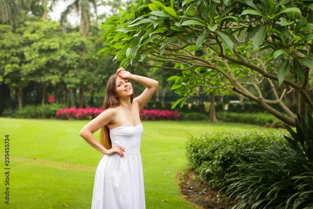 portrait of carefree young woman in white dress posing in green summer park portrait of carefree young woman in white dress posing in green summer park