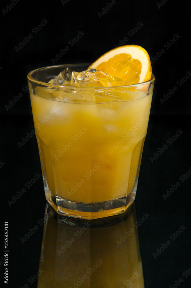 Orange juice in the glass. Reflection. Dark background. Isolated. Orange juice in the glass. Reflection. Dark background. Isolated.