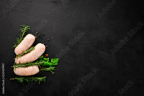 Raw sausages with spices and herbs. Barbecue. On a black stone background. Top view. Free copy space. photo