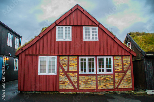 View of traditional red historic wooden house/building with grass (turf) roof in capital town of Faroe Islands - Tórshavn , Streymoy Island. Tourist popular attraction/place in Faroe Islands (Denmark)