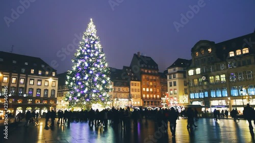 Christmas market in Strasbourg with tall beautiful illuminated tree in old town square, footage at night in winter with city lights and decorations, European tradition, Alsace